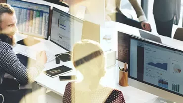 People working at desks with computers displaying graphs.