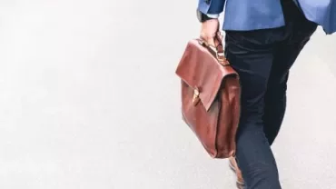 Person med en brun läderportfölj på promenad.