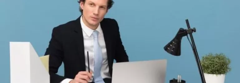 Man i kostym vid ett skrivbord med laptop och lampa
